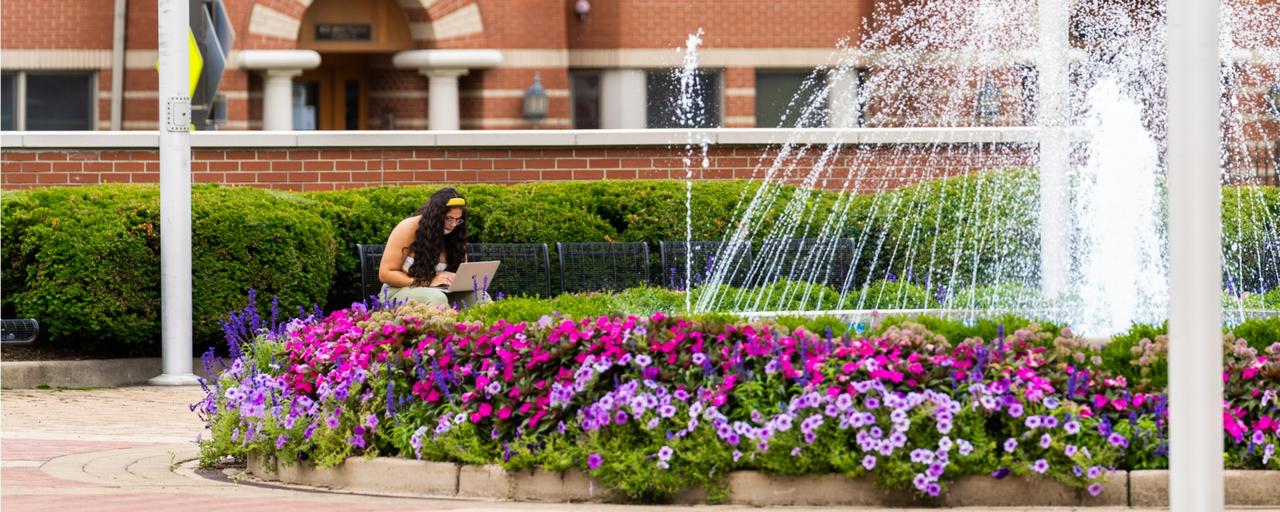 GVSU DeVos Center fountain w student studying in background